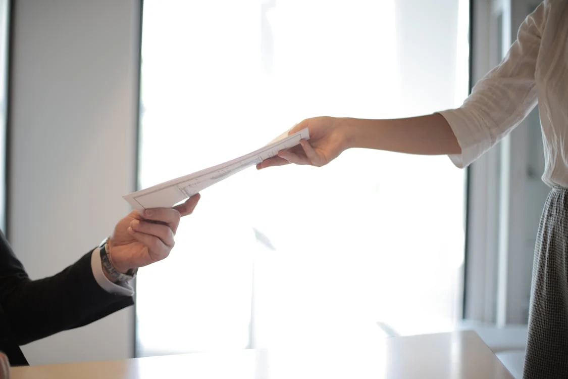 photo of someone handing a document to another person